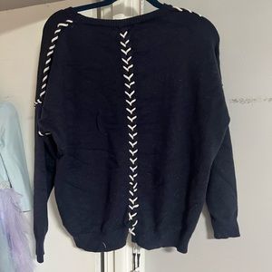 Navy blue sweater with white stitching up the arms and back